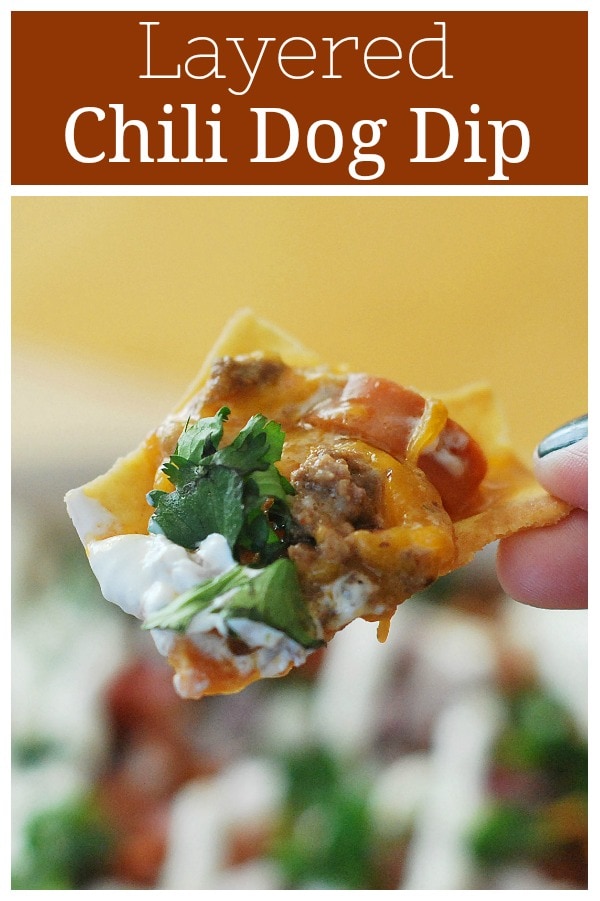 7 Layer Chili Cheese Dog Dip - perfect for football season! Layers of chili, hot dogs, bacon, cheese, sour cream, red onion, and cilantro - it's so delicious!
